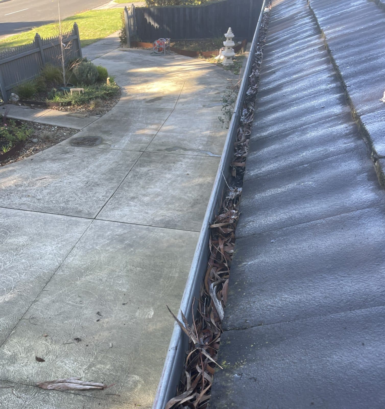 Gutter run before the Clearline service — the channel packed end to end with dry eucalyptus leaf litter